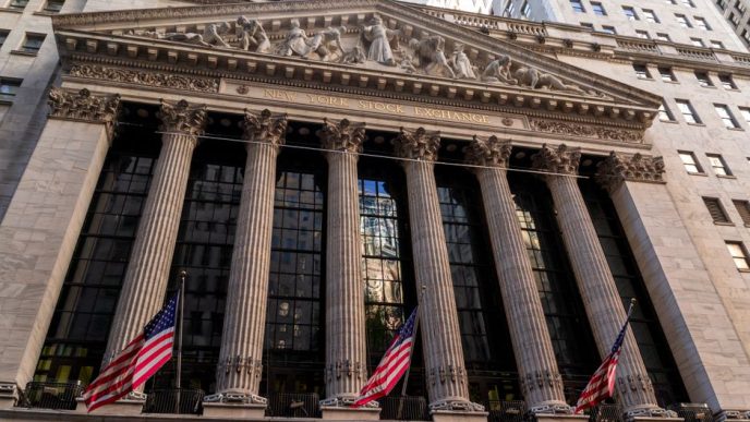 Iconic neoclassical facade of the New York Stock Exchange with American flags.