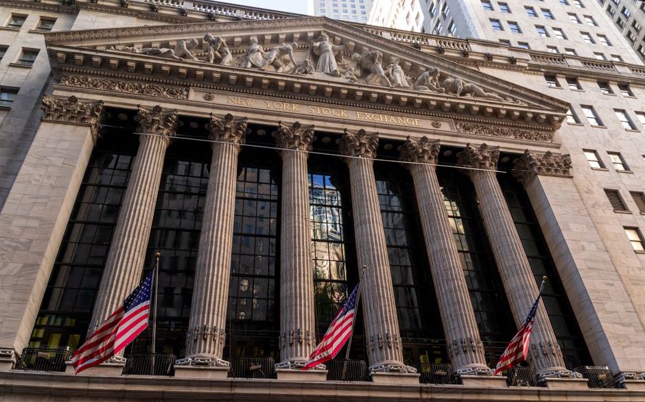 Iconic neoclassical facade of the New York Stock Exchange with American flags.